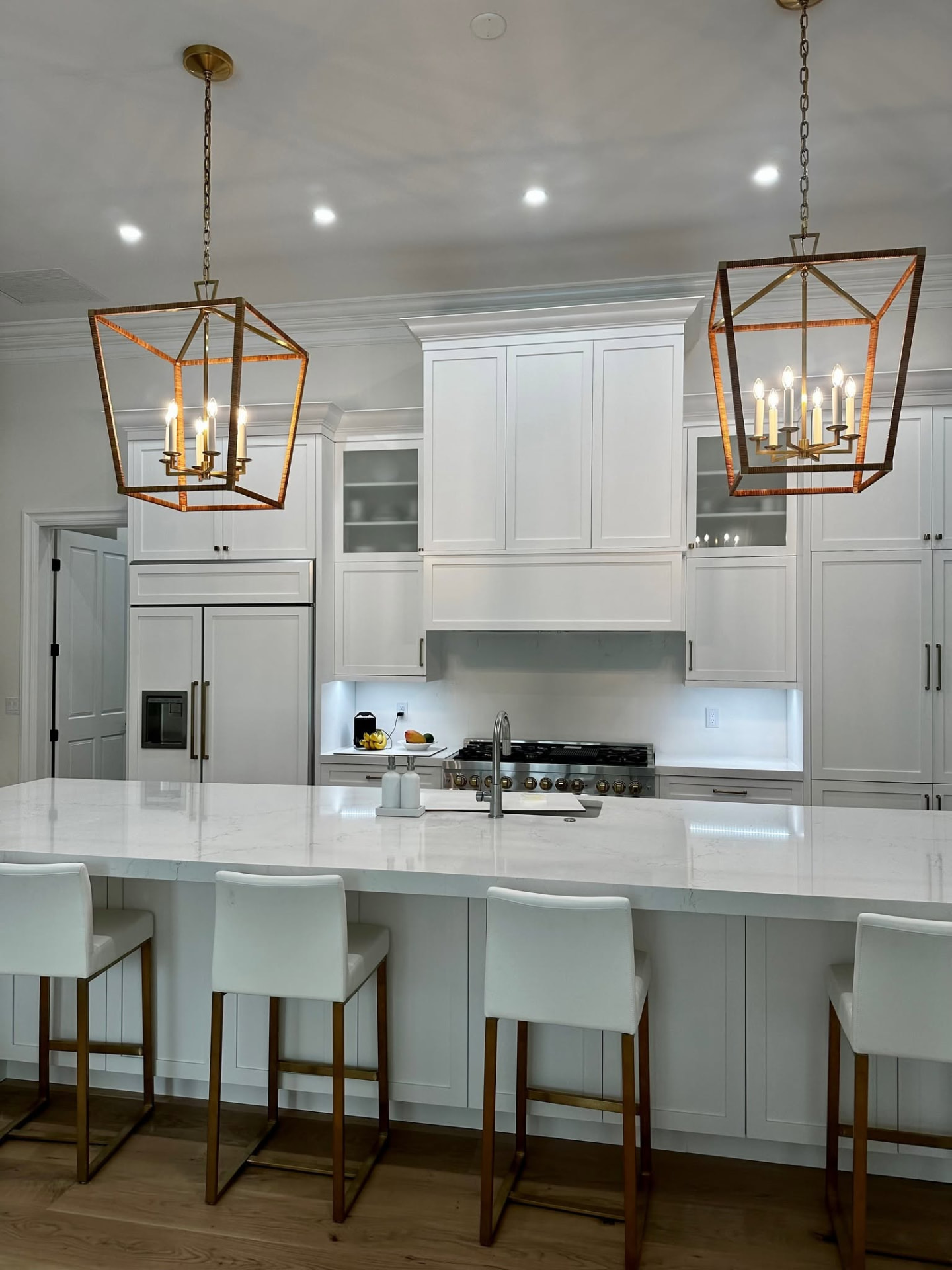 Finished kitchen project with two warm brass pendant lights over a marble island